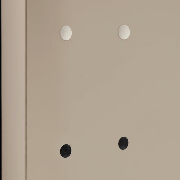 Quatre trous circulaires dans une surface beige, deux recouverts de capuchons blancs et deux de capuchons noirs, mettant en valeur les couvre-trous de meubles.