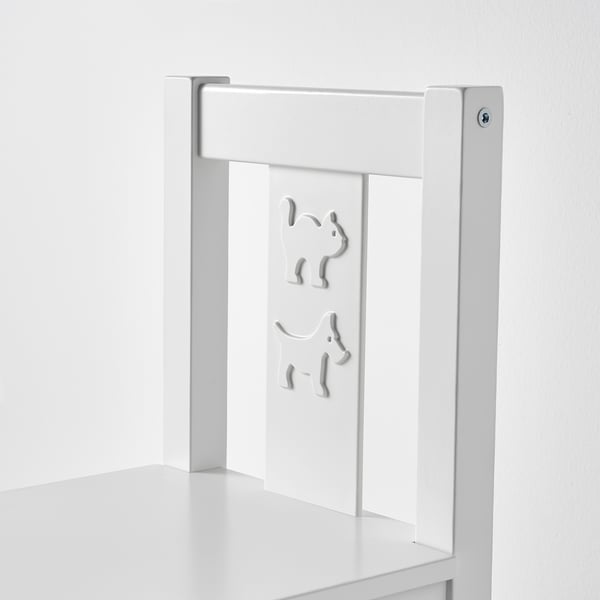 Une chaise d’enfant blanche élégante faite de matériaux robustes, avec des découpes décoratives sur le dossier.