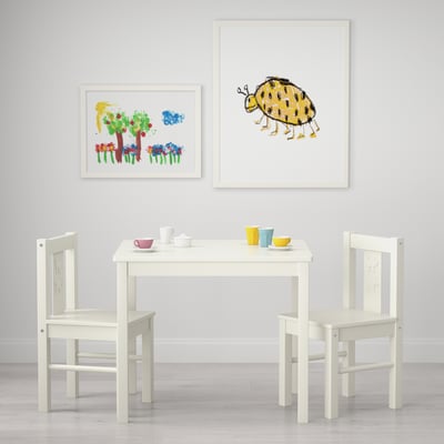 Installation de table pour enfants avec des chaises, des tasses et des impressions d’art. Convient pour l’artisanat et le jeu.