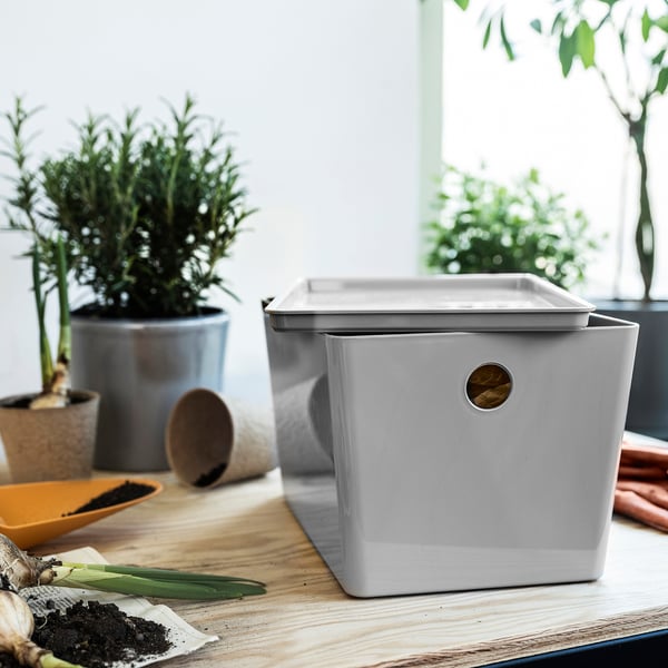 KUGGIS boîte gris clair sur table en bois avec des plantes. Plastique PET recyclé, conception rectangulaire et empilable. Plus petit qu’une plante en pot.