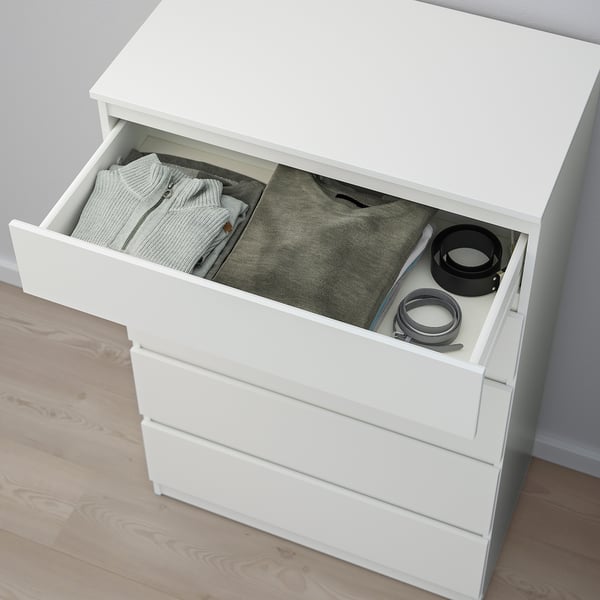 Commode blanche avec un tiroir ouvert laissant apparaître des vêtements pliés et de petits objets. Il comprend un kit d’ancrage pour plus de sécurité.