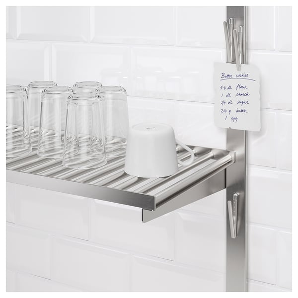 Étagère en métal dans la cuisine avec verres, tasse et note de recette fixée magnétiquement.