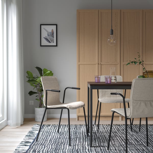 Salle à manger moderne avec chaises LÄKTARE grises, armoire en bois, table, plante et tapis.