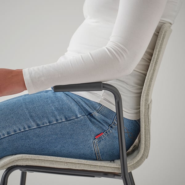 Personne assise sur une chaise de bureau, montrant les accoudoirs et le revêtement en tissu.