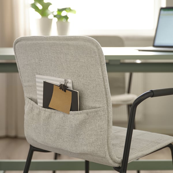 Chaise de bureau moderne avec poche pour ordinateur portable, accoudoirs noirs, près du bureau avec ordinateur portable.