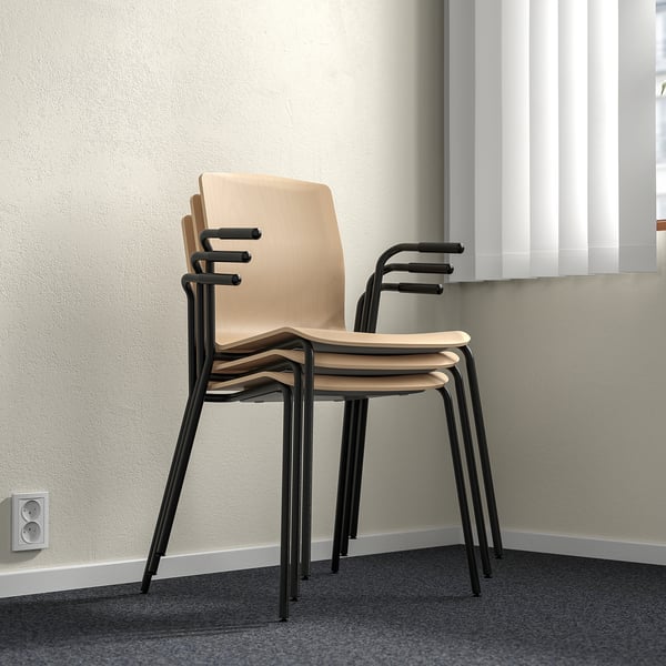 Trois chaises LÄKTARE empilées, placage de bouleau clair avec pieds en métal noir, exposées contre un mur.