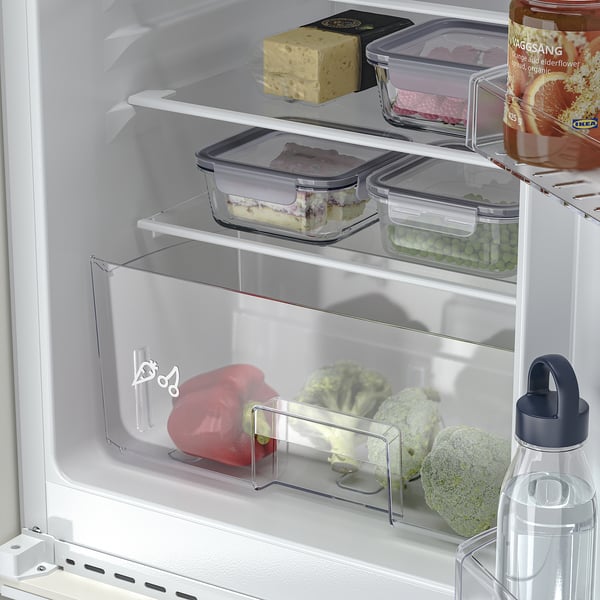 Réfrigérateur ouvert avec produits frais et étagères réglables.
