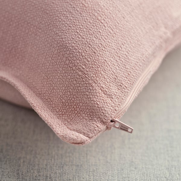 Gros plan d’une housse de coussin rose pâle avec surface texturée et fermeture éclair.