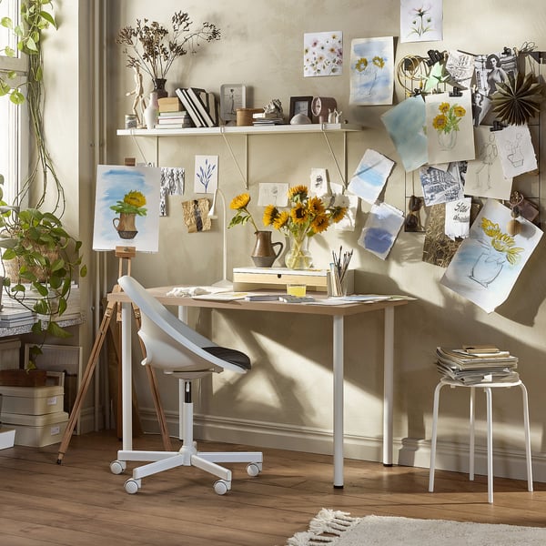 Studio d’art avec table LAGKAPTEN , chaise, fournitures artistiques, tournesols, croquis et lumière naturelle.