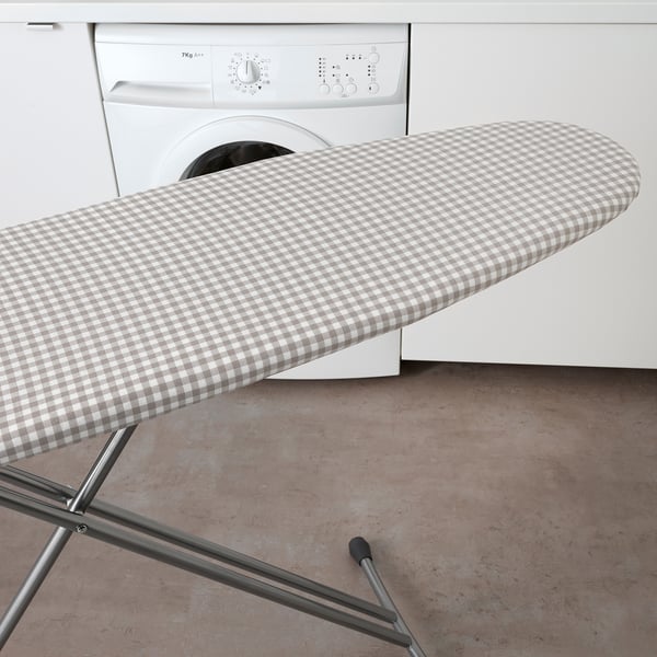 L’image montre une planche à repasser avec une nouvelle housse présentant un motif à carreaux, améliorant la douceur du repassage.