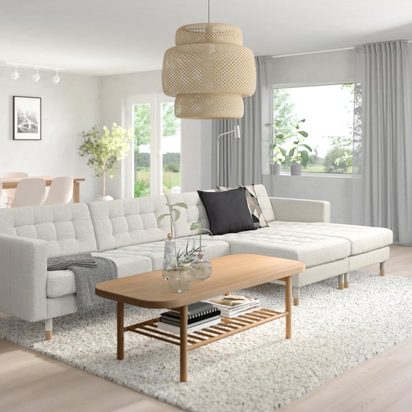 Salon minimaliste avec canapé LANDSKRONA, table basse et suspension, éclairé par de grandes fenêtres avec rideaux.