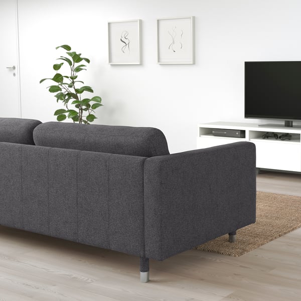 Le grand canapé sectionnel gris LANDSKRONA domine la pièce, contrastant avec les petites plantes, l’art minimaliste et la télévision à écran plat sur support blanc.