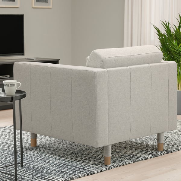Fauteuil LANDSKRONA gris dans le salon, élégant et moderne avec des pieds en bois, sur un tapis à motifs à côté d’une petite table avec une tasse.