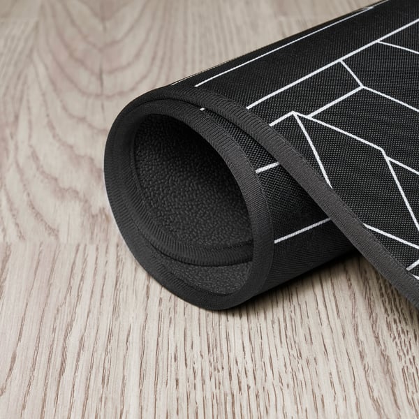 Tapis de chaise de chaise gaming enroulable noir à motif géométrique, mettant en valeur son dessous texturé pour plus de stabilité.