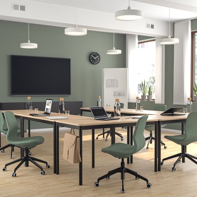 Bureau moderne avec chaises LÅNGFJÄLL, vert et bois clair. Grande télévision, plantes et lumière naturelle.