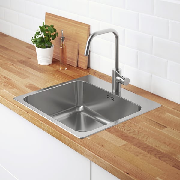 Évier de cuisine moderne avec robinet en acier inoxydable, comptoir en bois, plante et savon.
