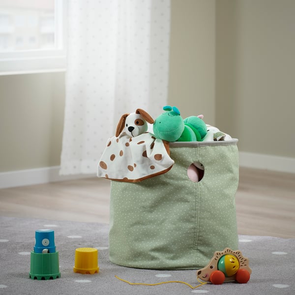 Poubelle à jouets avec des animaux en peluche sur tapis. Vert clair avec pois et poignées.