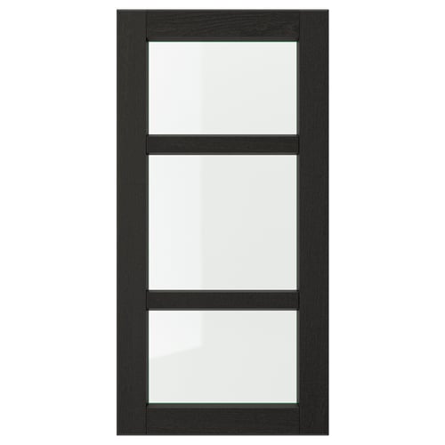 Une porte d’armoire de cuisine LERHYTTAN noire avec un cadre en bois massif et des panneaux en verre transparent, mettant en valeur un design traditionnel.