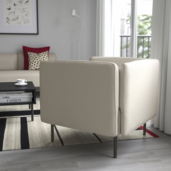 Salon moderne avec canapé LILLEHEM, grande fenêtre, table basse noire et oreiller rouge. Mur gris avec lampe et art.