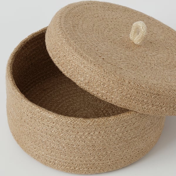 Panier en jute tressé à la main avec couvercle, mettant en valeur un savoir-faire de haute qualité. Texture naturelle et variations de couleurs, cousues de manière experte, idéales pour le stockage.