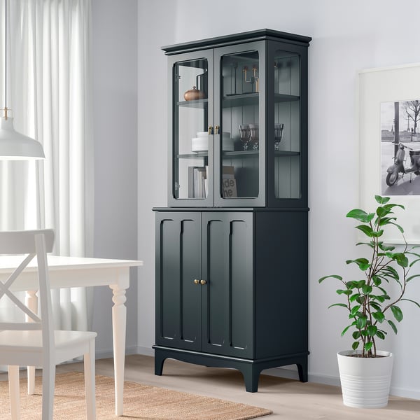 Armoire verte avec portes vitrées dans la salle à manger, à côté de la plante et de la table.