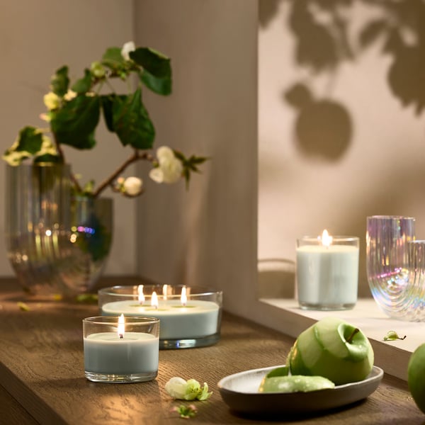 Bougie parfumée Lotsfägel, bleu clair, verre, ronde, sur une table en bois avec des fruits.