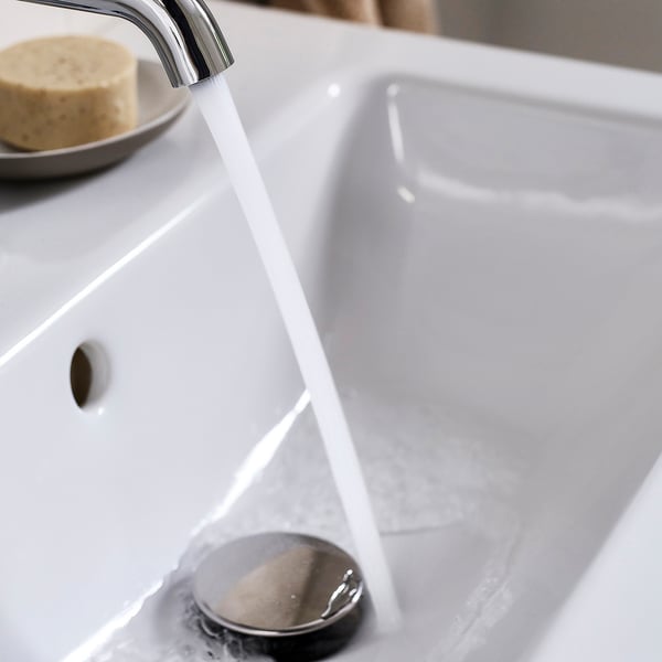 L’eau s’écoule du robinet chromé vers l’évier moderne, mettant en valeur son design élégant et efficace.