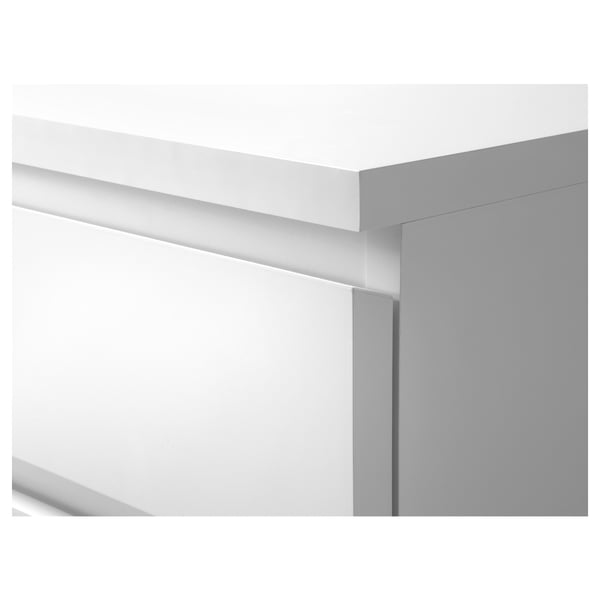 Commode blanche moderne aux lignes épurées et aux tiroirs, l’un légèrement ouvert.