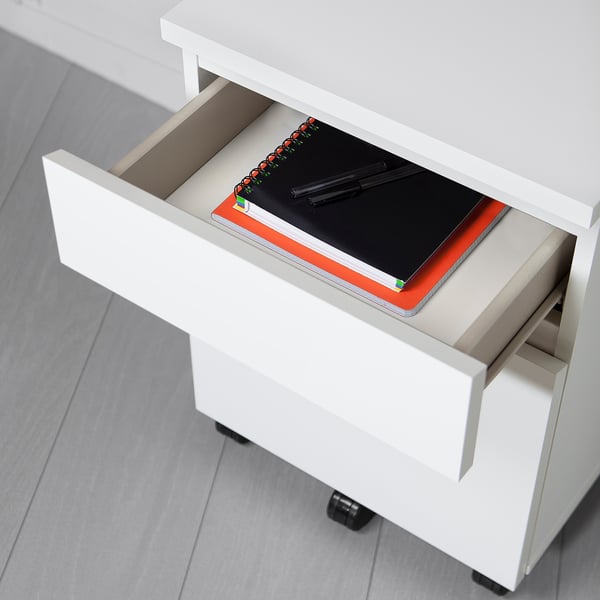 Meuble à tiroirs MALM blanc sur roulettes avec cahier et stylos à l’intérieur, prêt à l’emploi.