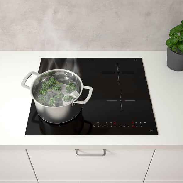 Cuisine moderne avec plaque à induction faisant bouillir le brocoli, commandes numériques, quatre zones de cuisson.