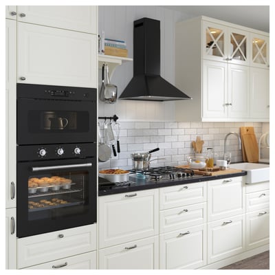 Cuisine moderne avec four double, cuisinière noire élégante, armoires blanches, ustensiles en bois et ustensiles de cuisine suspendus.
