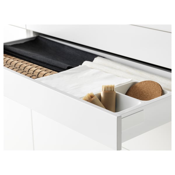 Le tiroir blanc, entièrement extensible, permet de ranger des ustensiles en bois et un dessous de plat en liège, doté d’un mécanisme de fermeture silencieux.