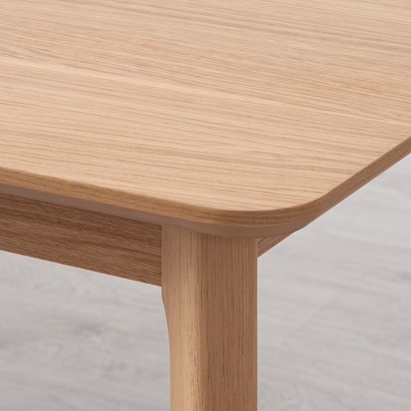 Table en bois clair en gros plan, présentant une texture de grain lisse et naturelle et des bords arrondis, mettant en valeur la qualité de l’artisanat et de la finition.
