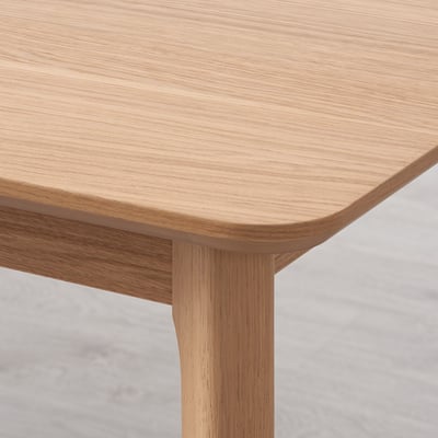 Table en bois clair en gros plan, présentant une texture de grain lisse et naturelle et des bords arrondis, mettant en valeur la qualité de l’artisanat et de la finition.