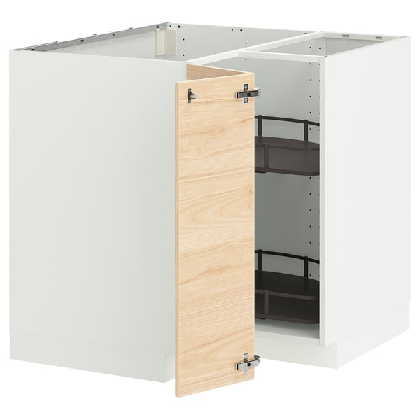 Un meuble de cuisine ikea METOD blanc avec une porte ouverte en bois de frêne clair, révélant des étagères noires réglables à l’intérieur.