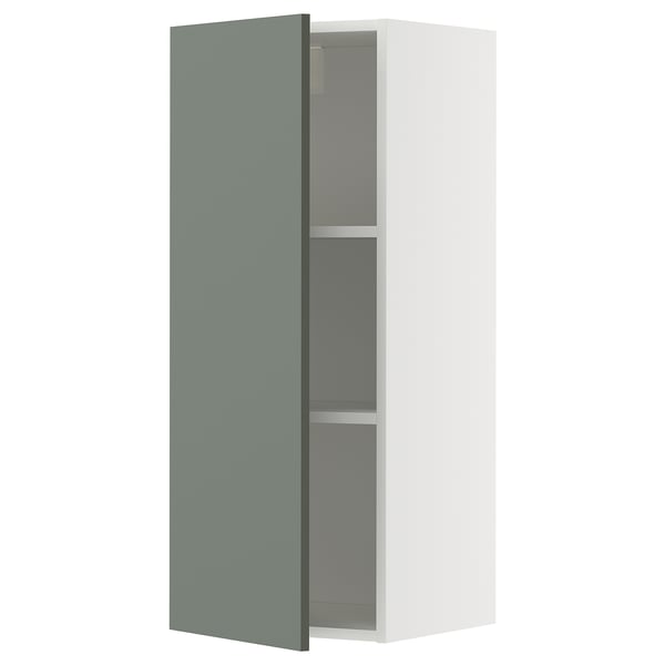 Une armoire murale METOD en blanc avec une porte gris-vert. Il a deux étagères à l’intérieur et est de conception moderne.