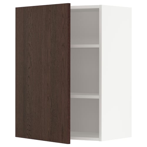 Une armoire murale de cuisine METOD blanche avec une porte brun foncé ouverte, révélant deux étagères à l’intérieur. La porte a une bordure en bois massif et une finition en placage de chêne.