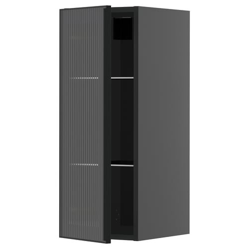 Une armoire de cuisine moderne noire avec une porte en verre dotée d’un cadre en métal et d’un design de roseaux verticaux, faisant partie du système METOD.