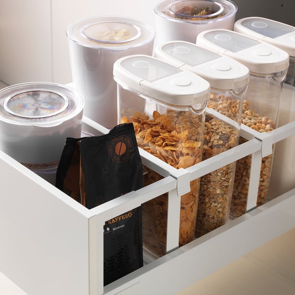 Tiroir de cuisine avec des récipients transparents, contenant des céréales et des sacs de café, organisés pour un accès facile.