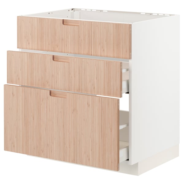 Un meuble de cuisine ikea METOD avec trois tiroirs en bambou clair. Il s’agit d’un design moderne et minimaliste avec des poignées élégantes.