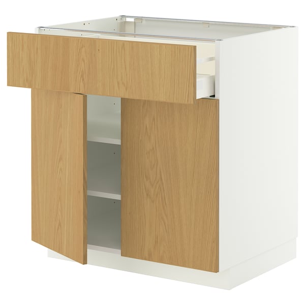Un meuble de cuisine en bois blanc et clair avec un tiroir partiellement ouvert.