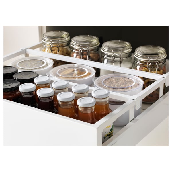 Armoire blanche avec étagères réglables, contenant des bocaux et des conteneurs, mettant en valeur le rangement organisé de la cuisine.