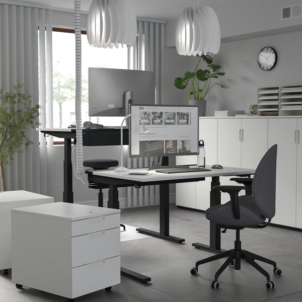 Bureau moderne avec bureau noir METTZON, deux moniteurs, chaise ergonomique et lumières élégantes.