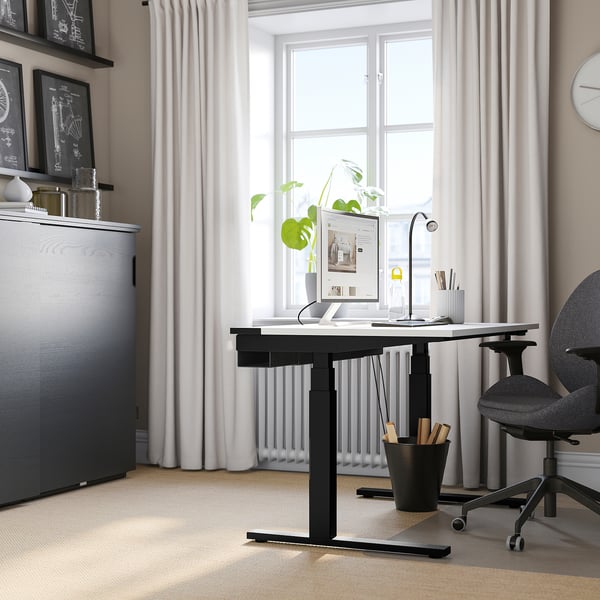 Bureau minimaliste avec bureau MITZZON, moniteur, clavier, lampe, plantes. Chaise grise, organisateur sombre, murs blancs, grande fenêtre.