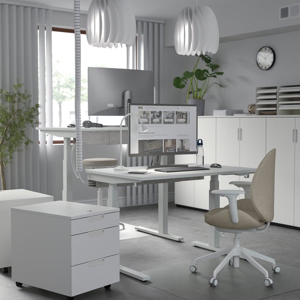 Bureau à domicile minimaliste : bureau debout, chaise ergonomique, plantes, tons neutres.