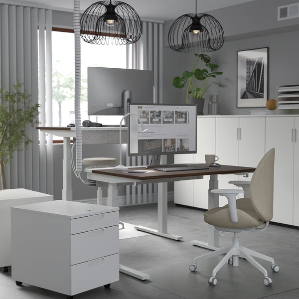 Configuration moderne du bureau à domicile avec bureau assis/debout blanc MITTZON et chaise beige ergonomique. Deux moniteurs, suspensions noires élégantes, plante verte.