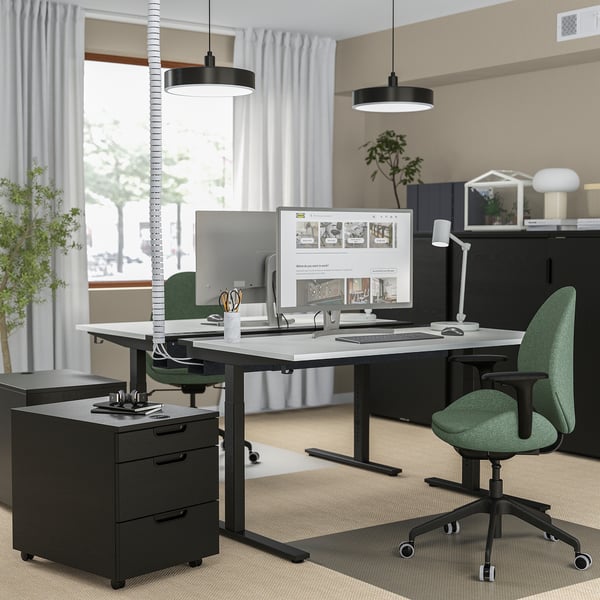 Bureau ajustable noir moderne avec ordinateur, classeur et chaise verte.