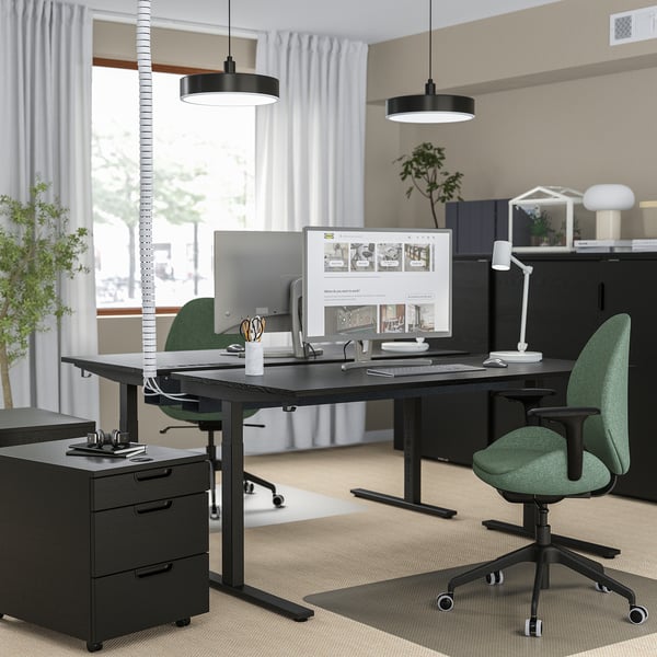 Bureau à domicile moderne avec bureau noir METTZON, chaises vertes, grands écrans, organisé avec un design minimaliste.