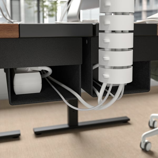 Bureau ajustable noir avec gestion des câbles blancs.