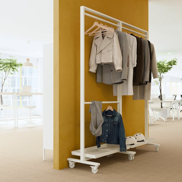 Le porte-vêtements MITTZON en blanc peut contenir des vestes et du denim, contre un mur jaune, 2 niveaux.
